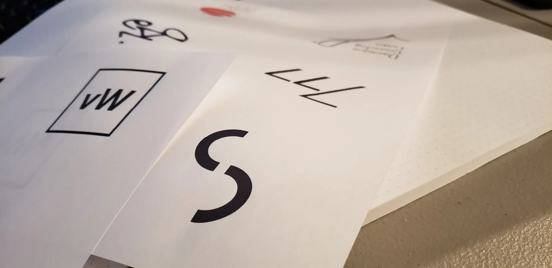 Printed logo sketches on a desk, including the Constant Studios mark