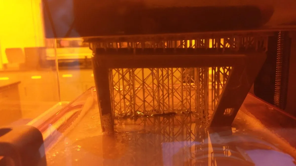 Resin 3D print on its build plate under orange light