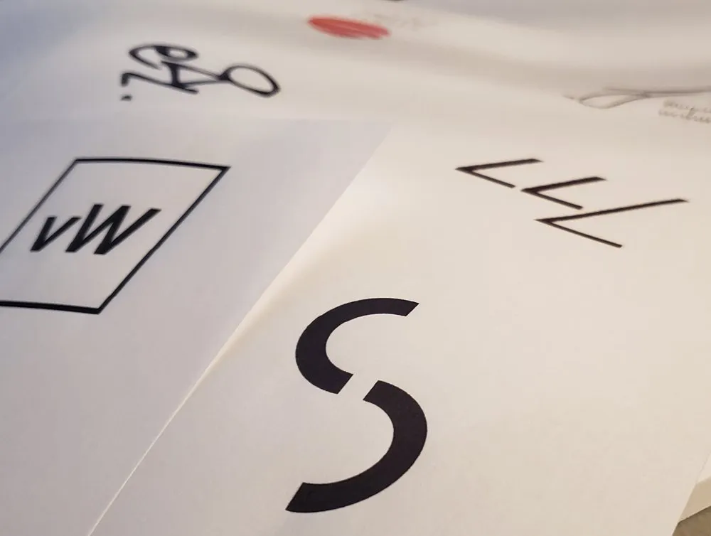 Printed logo sketches on a desk, including the Constant Studios mark